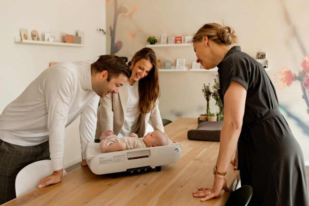ouders wegen baby in kraamweek met verloskundige