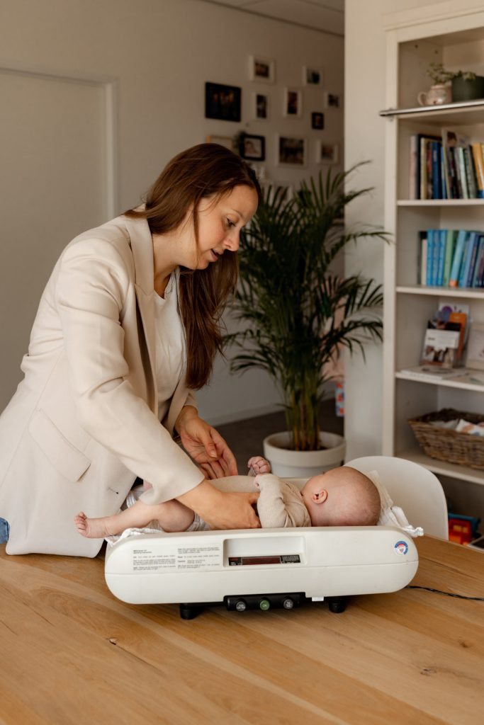Moeder weegt pasgeboren baby in kraamweek